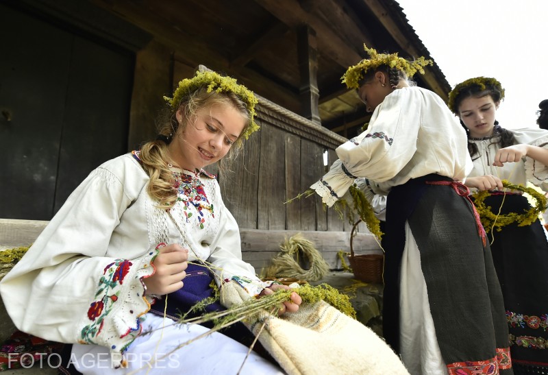 Membri ai ansamblului Vatra Harmanului impletesc coronite din flori, in incinta Muzeului National al Satului 'Dimitrie Gusti', locul de organizare al evenimentul cultural 'La portile soarelui. Sanzienele'.